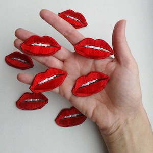 Könnte beinhalten: Ein Set mit neun roten, gestickten Bügeletiketten in Form von Lippen mit weißen Zähnen.