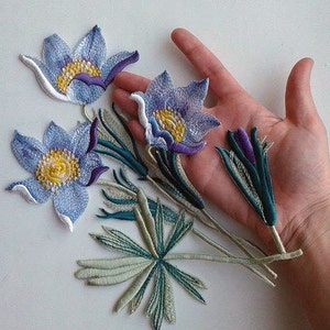 May include: A set of five embroidered patches featuring blue and purple flowers with green leaves. The patches are perfect for adding a touch of nature to clothing, bags, or other crafts.