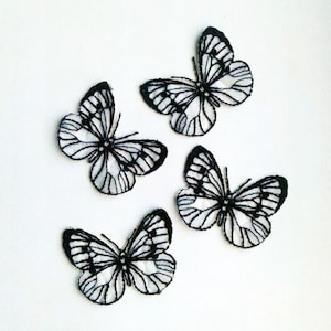 May include: Four black embroidered butterfly patches on a white background. The butterflies have a delicate, intricate design.