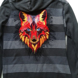May include: Black and white striped hooded sweatshirt with a red, yellow and purple embroidered fox on the back.