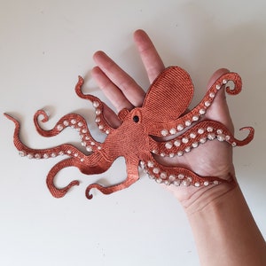 May include: A brown octopus applique with white polka dots. The octopus has eight tentacles and is in a curled position.