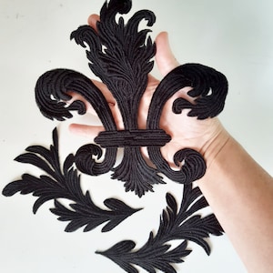 May include: Black velvet fabric appliques in the shape of a fleur-de-lis and leaves. The appliques are perfect for adding a touch of elegance to clothing, bags, or home decor projects.