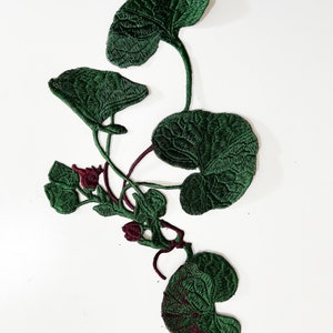Puede incluir: Aplique de tela bordada verde de una planta de hojas con tallos y capullos burdeos.