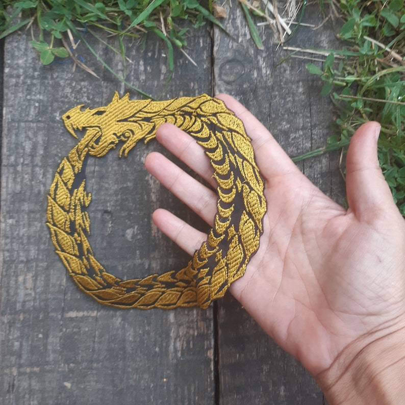 May include: Gold embroidered iron-on patch of a dragon curled in a circle.