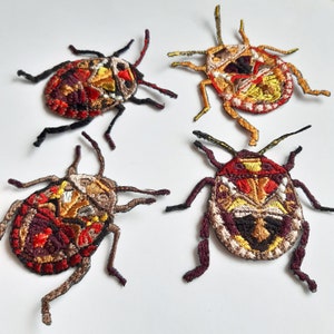 Pode incluir: Quatro patches bordados para passar a ferro que representam insetos coloridos. Os patches são em tons de vermelho, laranja, amarelo, castanho e preto. Os insetos têm detalhes intrincados e são perfeitos para adicionar um toque único a roupas, malas ou outros artigos de tecido.