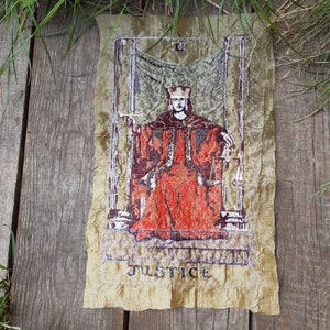 May include: Embroidered tarot card depicting Justice, a figure in a red robe holding a sword and scales, with the word "JUSTICE" at the bottom.