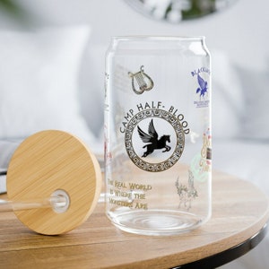 May include: A clear glass can with a wooden lid. The can has a gold design with the words "Camp Half-Blood" and a winged horse. The text "The real world is where the monsters are" is also printed on the can.