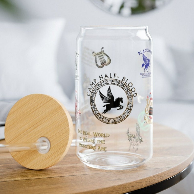 May include: A clear glass can with a wooden lid. The can has a gold design with the words "Camp Half-Blood" and a winged horse. The text "The real world is where the monsters are" is also printed on the can.
