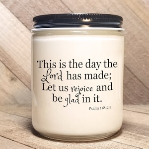 May include: White candle jar with a black lid. The jar has a quote printed on it: "This is the day the Lord has made; Let us rejoice and be glad in it. Psalm 118:24"