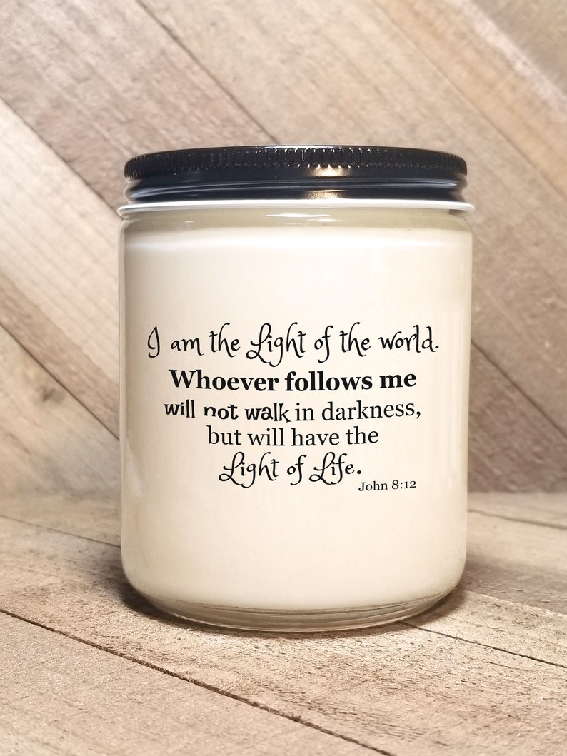 May include: White candle jar with a black lid. The jar has a quote printed on it: "I am the Light of the world. Whoever follows me will not walk in darkness, but will have the Light of Life. John 8:12"