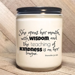 May include: A white candle with a black lid and a quote from Proverbs 31:26 that reads "She opens her mouth with wisdom, and the teaching of kindness is on her tongue."