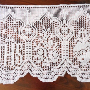 May include: White crocheted lace valance with a scalloped bottom edge and a repeating pattern of floral designs.