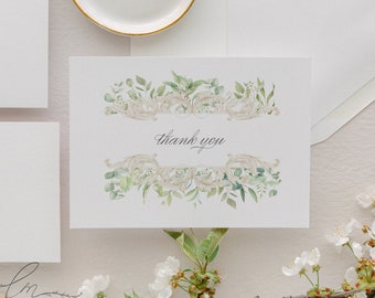 May include: A white card with a green and gold floral design and the text "thank you" in black calligraphy.