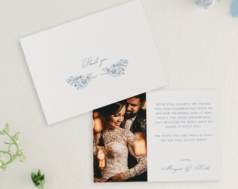 May include: A wedding thank you card featuring a photograph of the bride and groom. The card has a blue floral design and the text "Thank you" at the top. The text on the card reads "With full hearts, we thank you for celebrating with us on our wedding day. It was truly the most memorable day because we were able to share it with you. We hope you are well & that we see you again soon. Love, Margaret & Keith."