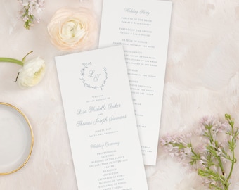 May include: A wedding ceremony program with a light blue floral design and the names Lisa Michelle Baker and Thomas Joseph Simmons. The program lists the wedding party, the wedding ceremony order, and the date and location of the wedding.