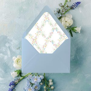 May include: A light blue envelope with a floral patterned interior, surrounded by white and blue flowers on a light blue background. The envelope is open, revealing the patterned interior.