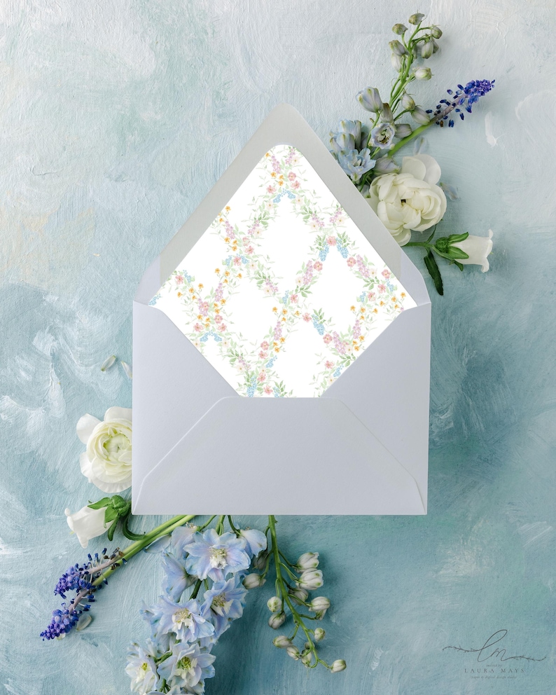 May include: A white envelope with a floral patterned interior, surrounded by white and blue flowers on a light blue background. The envelope's interior features a delicate grid of pastel flowers. The image has a soft, artistic aesthetic.
