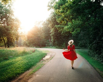 Girl walking in red dress down forest path