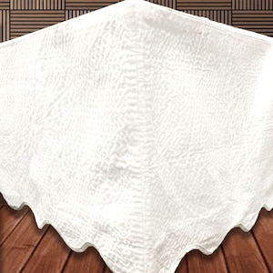 May include: White ruffled bed skirt with a quilted texture. The skirt is made of a soft, luxurious fabric and is perfect for adding a touch of elegance to any bedroom.