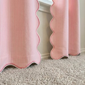 May include: A pair of curtains featuring a vertical pink and white pinstripe pattern. The fabric panels are finished with a distinct scalloped edge along the vertical side and bottom, highlighted by a thin white piping trim along the curved border.