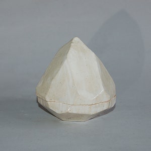 May include: A white ceramic diamond-shaped box with a textured surface.