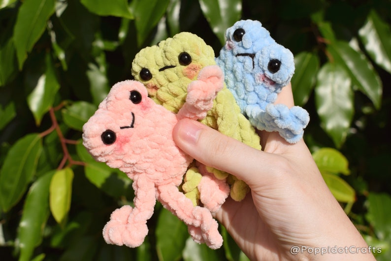 May include: Three small plush frog toys in pink, light green, and light blue. The frogs have embroidered eyes and mouths.