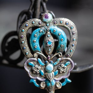 May include: A silver and blue butterfly-shaped hair pin with intricate details and colourful enamel accents.