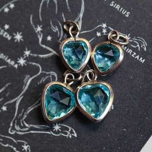 Puede incluir: Cuatro colgantes de plata en forma de coraz&oacute;n con piedras de cristal azul claro.