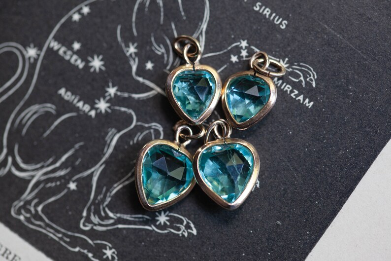 Puede incluir: Cuatro colgantes de plata en forma de coraz&oacute;n con piedras de cristal azul claro.