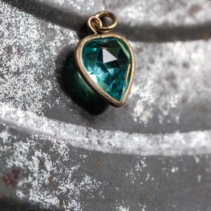 Puede incluir: Un colgante de coraz&oacute;n de oro con una piedra preciosa azul turquesa.