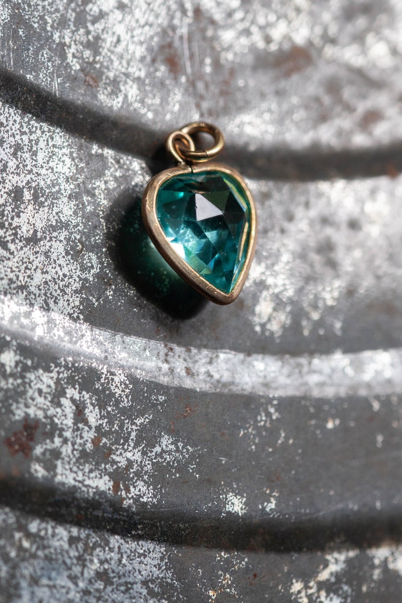 Puede incluir: Un colgante de coraz&oacute;n de oro con una piedra preciosa azul turquesa.