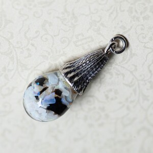 May include: A silver pendant with a clear glass orb filled with iridescent white and black shell pieces.