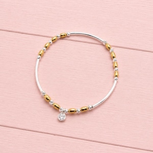 May include: A stretch bracelet featuring alternating gold-toned oval beads and small silver-toned spherical beads. The bracelet includes a single round, clear faceted charm hanging from the bottom, creating a circular design with metallic accents.