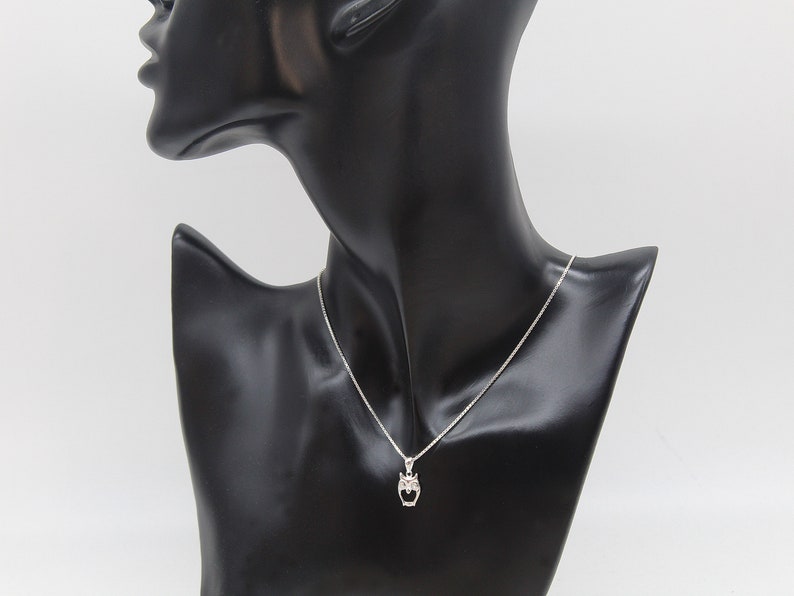 May include: A silver necklace with a small owl pendant. The owl is detailed with small, clear stones.