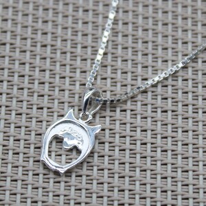 May include: Silver chain necklace with a silver owl pendant. The owl pendant has a cut-out design and is detailed with a small flower.