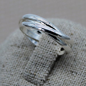 Peut inclure: Une bague en argent avec trois bandes entrelacées. La bague est lisse et polie.