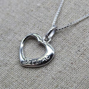 May include: A silver necklace with a heart-shaped pendant that says "Je t'aime" in cursive.