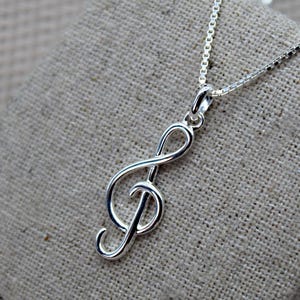Peut inclure: Un collier en argent avec un pendentif en forme de clé de sol. Le pendentif est un design simple et élégant.