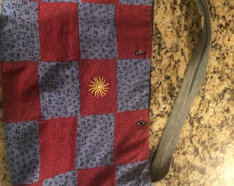May include: A red and blue patchwork tote bag with a sun design. The bag has a long denim strap.