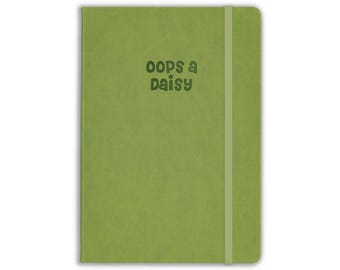 May include: A lime green notebook with a vertical elastic closure band. The front cover features the text "oops a daisy" printed in a dark green, rounded font. The notebook has a smooth, matte finish and a rectangular shape with rounded corners.