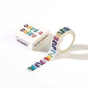 May include: A roll of decorative adhesive tape featuring a repeating pattern of colorful book spines in various shades. Next to the roll is a white square box labeled with the text Oops a Daisy and social media icons for Facebook, Instagram, TikTok, YouTube, and Pinterest.