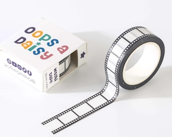 Może przedstawiać: Rolka taśmy washi z czarno-białym wzorem taśmy filmowej, w komplecie z białym kartonowym pudełkiem z napisem Oops a Daisy, ikonami mediów społecznościowych i tekstem 15mm x 10m, prezentującym ten sam wzór taśmy filmowej na taśmie wewnątrz.