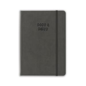 May include: A dark gray notebook with a smooth, matte cover featuring the text "oops a daisy" embossed in the center. The notebook includes a vertical black elastic band closure attached to the right side, keeping the covers securely closed.