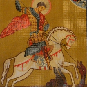 May include: A colorful embroidered artwork depicting Saint George slaying a dragon. The saint is on horseback, wearing armor and a red cloak, and holding a spear. The dragon is green and black with red accents.