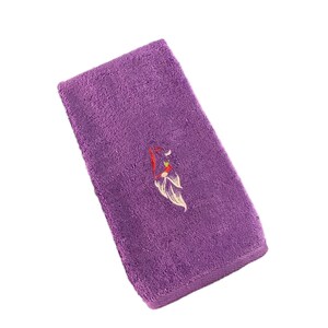 Könnte beinhalten: Lilafarbenes Handtuch mit einem gestickten Blumenmuster in Rot und Weiß.