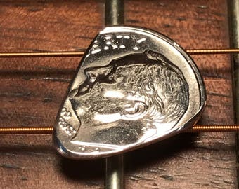 Könnte beinhalten: Eine silberne US-Dime-Münze, die zu einem Gitarrenplektrum umgewandelt wurde. Die Münze zeigt auf der einen Seite das Profil von Präsident Franklin D. Roosevelt und auf der anderen Seite die Worte "LIBERTY" und "IN GOD WE TRUST".