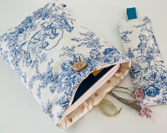 May include: A white book cover with a blue and white floral pattern. The cover has a button closure and a matching bookmark. The book cover is open to reveal a book with a blue cover.