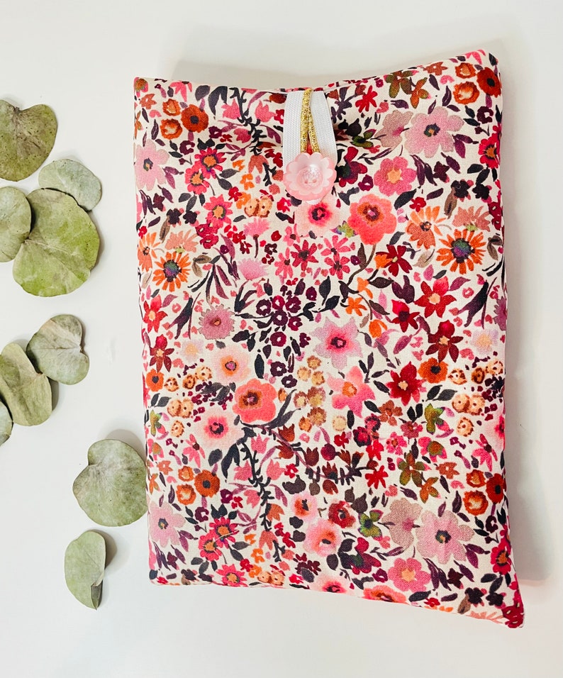 May include: A small, floral patterned pouch with a pink button closure. The pouch is made of a soft, cream-colored fabric with a variety of pink, red, and orange flowers.