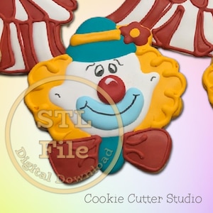 May include: A clown-shaped biscuit decorated with white icing, a red nose, a blue smile, yellow hair, a teal hat with a yellow band, and a red bow tie. The image features a circular overlay with the text STL File Digital Download.