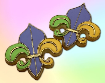 May include: Two purple, green, and gold fleur-de-lis cookies.